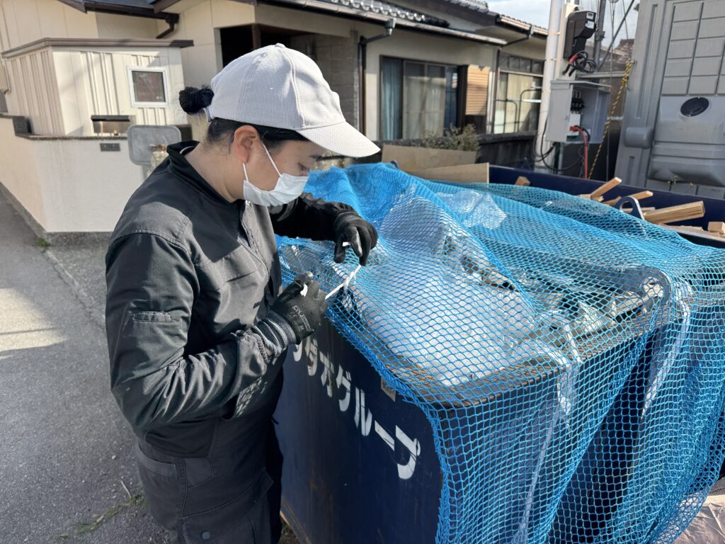 ゴミ箱にかぶせたネットをひもで縛って固定する様子