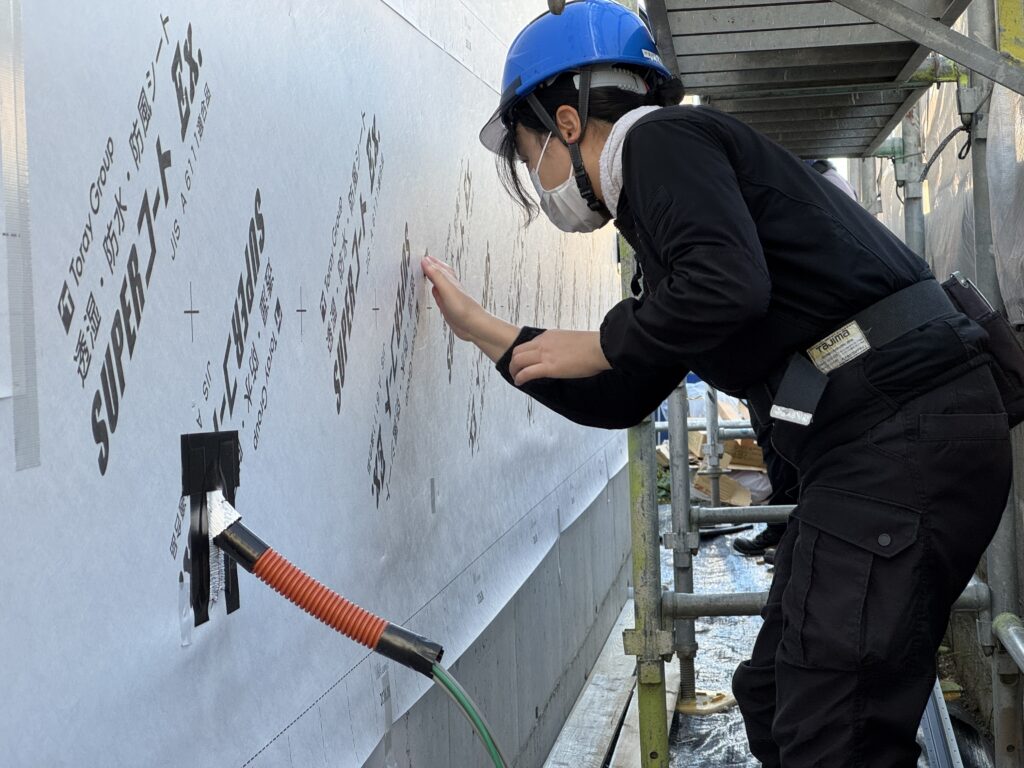 透湿防水シートに小さな穴がないか手で触れて確認する様子